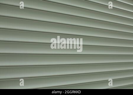 Jalousien-Struktur auf der Straße. Kunststoffoberfläche für die Fenster. Gerippte lange Lamellen. Grauer Hintergrund aus industriellem Material. Stockfoto