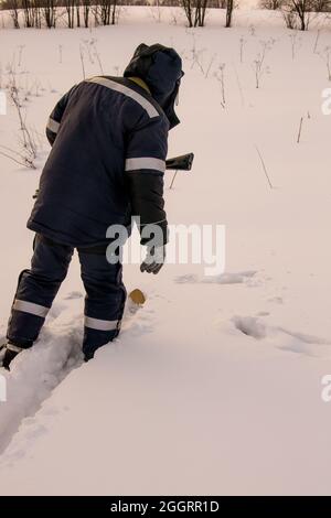 Ein Jäger oder Wilderer, der vom Scheitern mit einer Waffe enttäuscht ist, nähert sich den frischen Spuren eines Vogels im Schnee auf Skiern Stockfoto