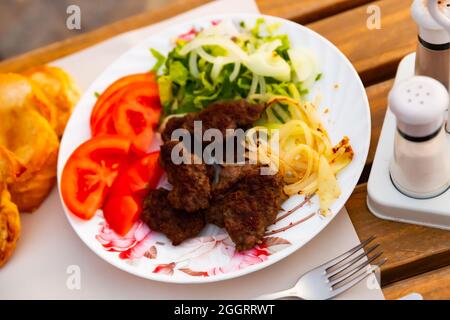 Türkische Kofte, gegrillte Kalbfleischbällchen mit Gemüse und Brot Stockfoto