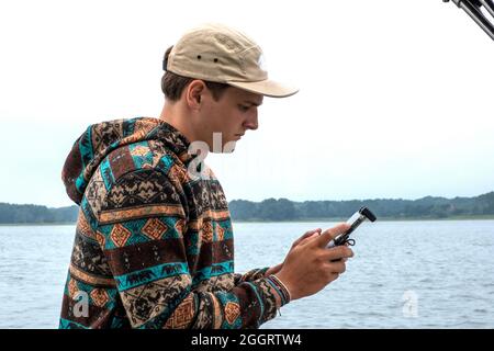 Junger Mann, der auf einem kleinen Boot Luftbilddrohne betreibt Stockfoto