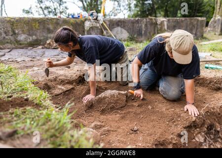 Natzwiller, Frankreich. August 2021. Zwei Mitarbeiter der Universität Straßburg nutzen Handinstrumente, um nach Artefakten und Hinweisen zu graben. Im ehemaligen Nazi-Konzentrationslager Natzwiller-Struthof führt ein Team der Universität Straßburg archäologische Ausgrabungen im Steinbruch und in der Lagerschmiede durch. Quelle: Philipp von Ditfurth/dpa/Alamy Live News Stockfoto