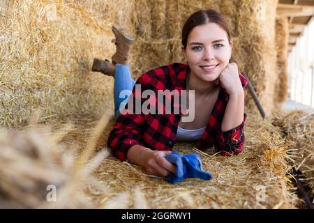 Frau, die auf dem Bauernhof bei Strohhalmen posiert