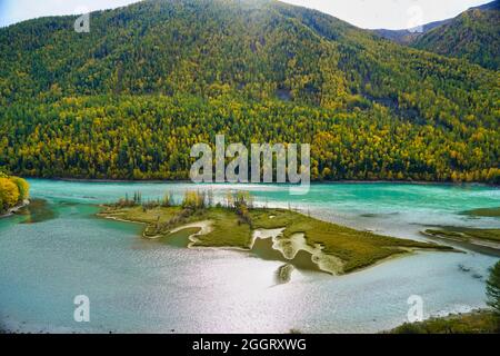 Wolong Bay of Kanas Lake. Kristallblauer Fluss, kleine Sandbank.Grüne Baumhügel. Die natürliche Schönheit des Paradieses. Kanas Nature Reserve. Xinjiang Provi Stockfoto