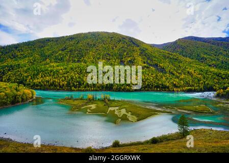 Wolong Bay of Kanas Lake. Kristallblauer Fluss, kleine Sandbank.Grüne Baumhügel. Die natürliche Schönheit des Paradieses. Kanas Nature Reserve. Xinjiang Provi Stockfoto