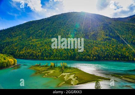 Wolong Bay of Kanas Lake. Kristallblauer Fluss, kleine Sandbank.Grüne Baumhügel. Die natürliche Schönheit des Paradieses. Kanas Nature Reserve. Xinjiang Provi Stockfoto