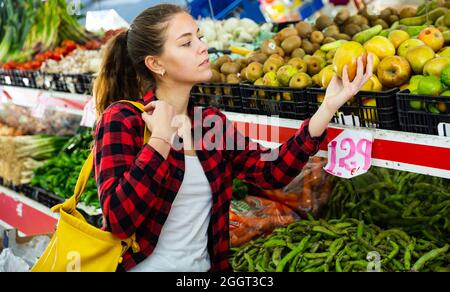 Porträt einer jungen Kundin im Laden in der Nähe der Theke mit einem Apfel Stockfoto