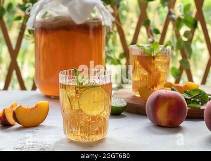 Kombucha-Tee leicht alkoholisches, leicht brausendes Getränk mit Pfirsich und Limette. Stockfoto