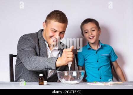 Konzept der chemischen aus- und Weiterbildung. Nahaufnahme eines Jungen und seines Vaters, die ein heimisches Experiment machten, Schleim aus Klebstoff, Natriumtetraborat A machten Stockfoto