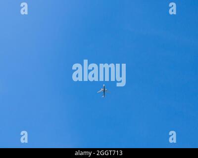 Ein Passagierflugzeug, das über den Kopf fliegt. Jet-Flugzeug, das tief mit blauem Himmel und Wolken im Hintergrund fliegt. Flugzeug fliegen in Tageszeit Stockfoto