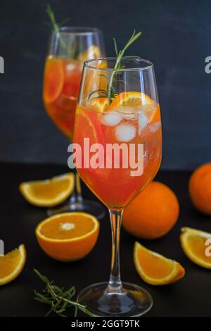 Aperol Spritz ist ein Sommergetränk, das in einem Glas mit aperol, Prosecco, Soda und Orangenscheibe serviert wird. Gläser eisiger Cocktail in einem Weinglas und einem Rosmarin Stockfoto