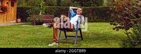 Der Mann sitzt in einem Liegestuhl in den Bergen Stockfoto