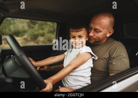 Vater lehrt den kleinen Sohn auf einer Autoreise zu fahren Stockfoto