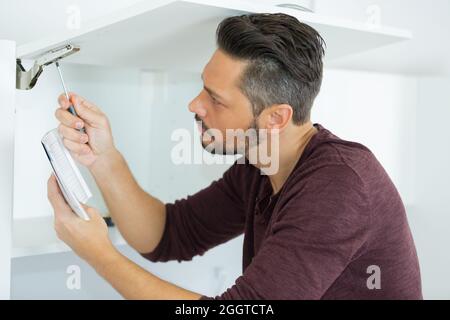 Mann montiert Schrank im neuen Haus Stockfoto