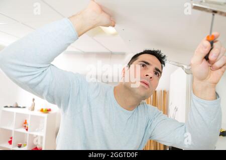 Einstellen des Türscharniers des Befestigungsschranks mit einem Schraubendreher Stockfoto