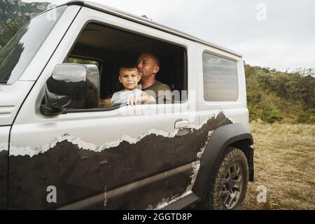 Vater lehrt den kleinen Sohn auf einer Autoreise zu fahren Stockfoto