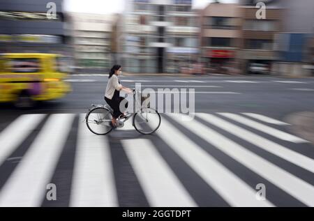 Tokio, Japan. September 2021. Eine junge Frau überquert einen Fußgängerüberweg auf einem Fahrrad im Stadtteil Nihionbashi. Quelle: Karl-Josef Hildenbrand/dpa/Alamy Live News Stockfoto