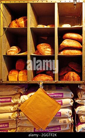 Frisch gebackene Bauernhaus knusprige Brote auf Regalen und Säcke von Bäckermehl Stockfoto