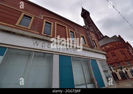 Geschlossen Geschäft auf Blackpool Promenade mit Blackpool Tower im Hintergrund, alte Woolworths Beschilderung sichtbar Stockfoto