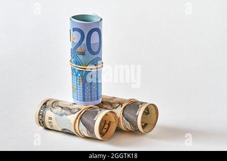 20-Euro-Rechnung, die als Tubuli auf 20-Dollar-Scheinen aufgewickelt wird. Das Konzept der Überlegenheit des Euro gegenüber dem Dollar. Nahaufnahme, selektiver Fokus Stockfoto