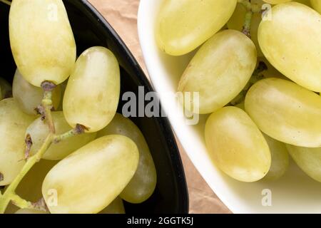 Mehrere Beeren von reifen süßen Trauben in schwarzen und weißen Keramikschalen, Nahaufnahme, Draufsicht. Stockfoto