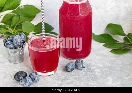 Pflaumenkompott in einem Glas. Im Hintergrund sind Pflaumen. Tkemali-Sauce. Vorbereitung auf den Winter. Heller Hintergrund. Speicherplatz kopieren. Stockfoto