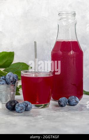 Pflaumenkompott in einem Glas. Im Hintergrund sind Pflaumen. Tkemali-Sauce. Vorbereitung auf den Winter. Heller Hintergrund. Speicherplatz kopieren. Stockfoto