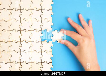 Weibliche Hand, die das letzte Puzzleteil in Position setzt. Abschlusskonzept. Stockfoto