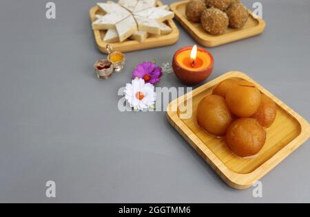 Diwali Diya, Süßigkeiten oder Mithai, und Blumen sind als festlicher Hintergrund angeordnet. Verschiedene Süßigkeiten Kaju Katli, Gulab Jamun und Churma laddu . Stockfoto