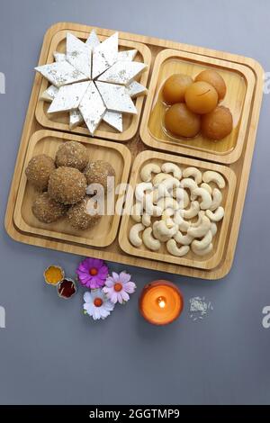 Diwali Diya, Süßigkeiten oder Mithai, und Blumen sind als festlicher Hintergrund angeordnet. Verschiedene Süßigkeiten Kaju Katli, Gulab Jamun und Churma laddu . Stockfoto