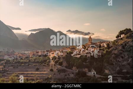 Panoramablick auf das Dorf Polop, Spanien bei Sonnenaufgang mit den Bergen in den Wolken im Hintergrund. Stockfoto