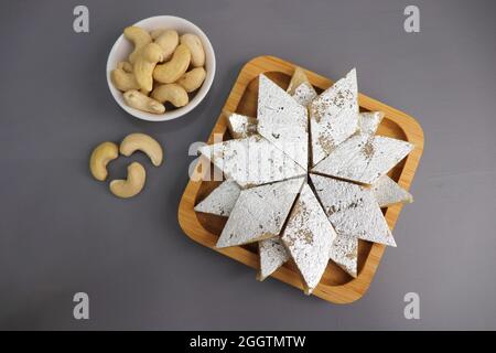 Kaju Katli ist eine traditionelle indische Diamant-förmige süße oder Mithai aus Cashewpaste, Zucker und mava oder Khoya. Serviert in einem Holzteller. Stockfoto