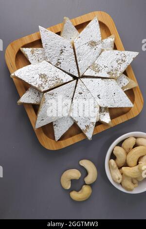 Kaju Katli ist eine traditionelle indische Diamant-förmige süße oder Mithai aus Cashewpaste, Zucker und mava oder Khoya. Serviert in einem Holzteller. Stockfoto