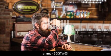 Mann trinkt Bier an der Bar. Menschen, Lebensstil, Erholung. Mann mit Bier. Bärtiger Hipster hält ein Glas Bier. Bierkneipe. Stilvoller Typ im Café Stockfoto