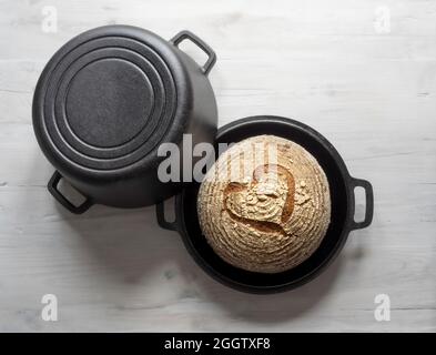 Glutenfreier Sauerteig gebacken in Gusseisen niederländischen Ofen Auflauf mit Herz-Design in Oberfläche der Kruste geritzt. Stockfoto