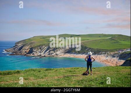 Frau mittleren Alters mit Strohhut vor dem Strand von el Sable de Tagle, Suances, Kantabrien, Spanien, Europa Stockfoto