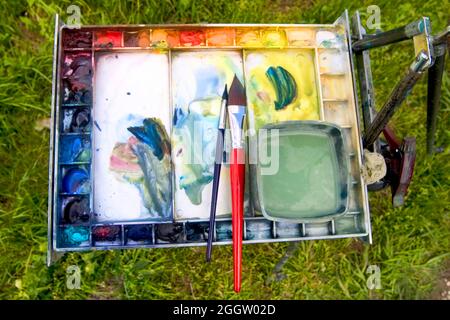 Aquarell-Farbkasten mit Pinsel in einer Wiese Stockfoto