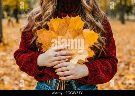 Gesichtsloses Porträt einer Frau mit Ahornblättern. Aktivitäten für Happy Fall, verbessern Sie sich, Möglichkeiten, glücklich und gesund Herbst. Das Leben Genießen Stockfoto