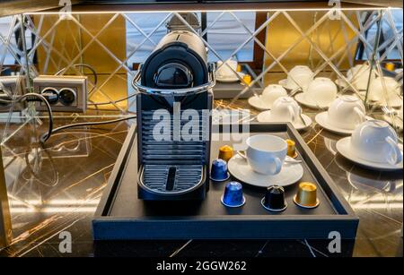 Espressomaschine und Station mit Tassen im Zimmer des Hotels Stockfoto
