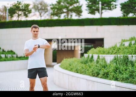 Athlet Runner mit Blick auf die Uhr des Herzfrequenzsensors. Mann überprüft sein Gadget vor dem Laufen Stockfoto