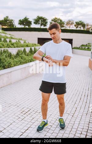 Athlet Runner mit Blick auf die Uhr des Herzfrequenzsensors. Mann überprüft sein Gadget vor dem Laufen Stockfoto