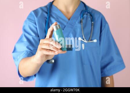 Krankenschwester hält Asthma-Inhalator auf rosa Hintergrund Stockfoto