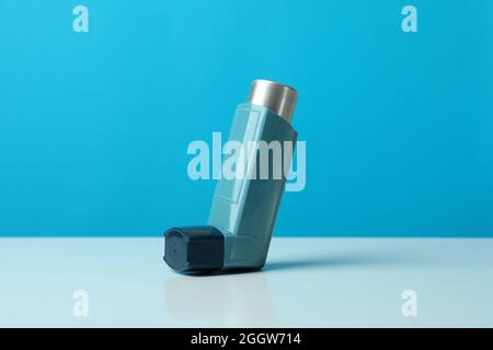 Asthma-Inhalator auf weißem Tisch vor blauem Hintergrund Stockfoto