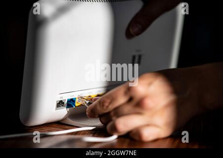 Berlin, Deutschland. September 2021. ABBILDUNG: Ein Mann schließt ein LAN-Kabel in den DSL-Steckplatz eines Wireless-Routers ein. Quelle: Fabian Sommer/dpa/Alamy Live News Stockfoto