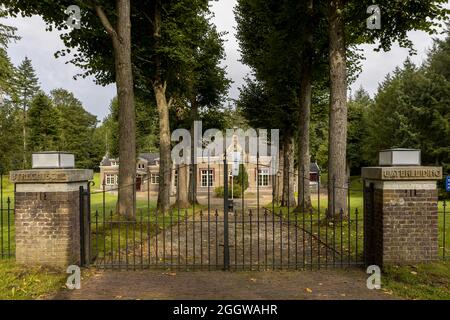 SOEST, NIEDERLANDE - 21. Aug 2021: Eingangstor flankiert von zwei Säulen mit dem Gebäude des niederländischen Frischwasserversorgungsunternehmens Viens in grünen Wäldern Stockfoto