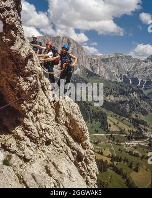 Diese Gruppe junger Erwachsener befindet sich am letzten Anflug zur Brücke über die Schlucht auf dem letzten Abschnitt des Klettersteiges Klettersteig Brigata Tridentina geschützter Klettersteig, der zum Rifugio Pisciadu in der Sellagruppe unweit des Grödner Jochs einführt Die italienischen Dolomiten von Südtirol. Stockfoto