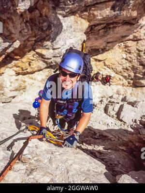 Ein junger Mann genießt sein Klettersteig-Erlebnis auf einem der vielen Klettersteige der Brenta-Dolomiten in der Nähe von Trient in Italien Stockfoto