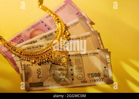 Goldene Juwelen auf indischen Geldscheinen. Stockfoto