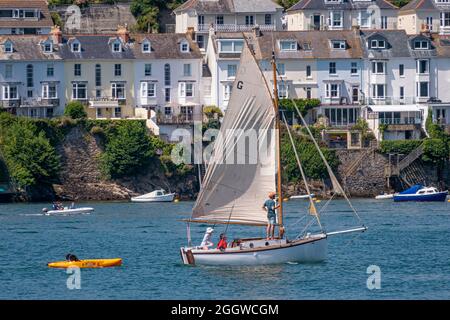 Eine kleine Yacht segelt sich an einem warmen Julitag den Fluss Fowey hinauf - Fowey, Cornwall, Großbritannien. Stockfoto