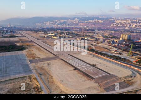 Haifa Flughafen und Start- und Landebahn mit der Skyline der Stadt im Hintergrund, Luftaufnahme. Stockfoto