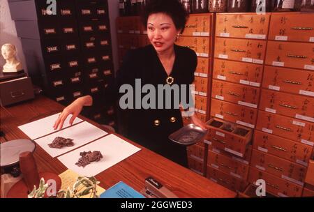 Austin Texas USA, um 1992: Frau entschrauben Deckel auf Krug mit Kräutern in einer chinesischen Kräuterapotheke in einer Akupunkturklinik. ©Bob Daemmrich Stockfoto